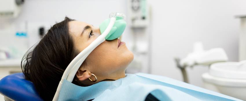 The image shows a woman in a dental chair wearing a nasal mask for conscious sedation